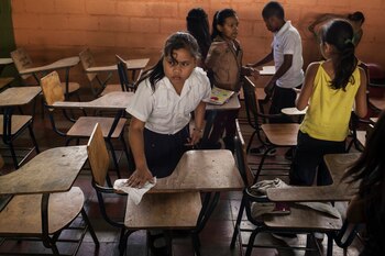 Una estudiante limpia su escritorio en el centro Pablo Portillo Figueroa en Nueva Suyapa.