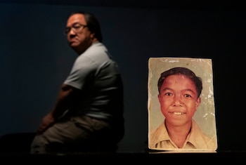 Una víctima de abuso sexual identificado con las iniciales C.M.V., 58, junto a una foto suya de cuando era niño, en Guam (AP Photo/David Goldman)