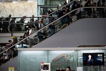 Los manifestantes cantan consignas mientras suben por las escaleras mecánicas del aeropuerto (Foto de Philip FONG / AFP)
