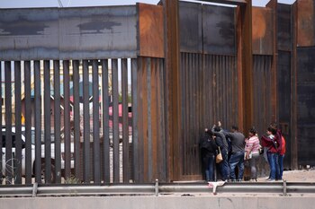 Migrantes centroamericanos se asoman en por el muro fronterizo en el tramo de Puente Nuevo, en Ciudad Juárez (México). (EFE/ Rey R. Jauregui)