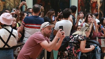 Hay muchos visitantes que no miran directamente la pintura, sino que lo hacen a través de la pantalla de su móvil (Owen Franken para The New York Times)