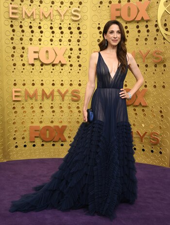 La Marin Hinkle optó para la alfombra violeta de los EMMY 2019 un diseño realizado en seda plisado con gran escote y transparencias que completó con pulseras plateadas, aros gota y clutch de raso